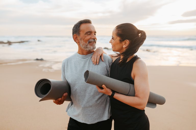 Positive senior caucasian family in sportswear with mat enjoy workout and active lifestyle on beach in morning, outdoor.