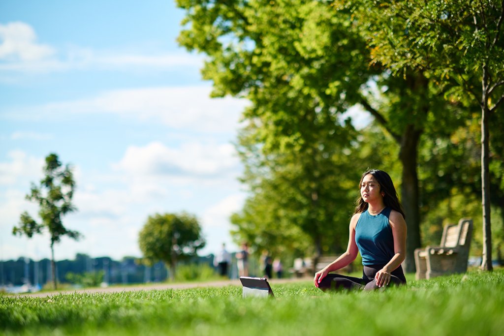 Woman doing yoga in the grass of a park.