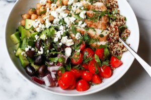 Greek bowl with tomatoes, feta, quinoa, chickpeas, cucumber, olives, red onion and herbs.