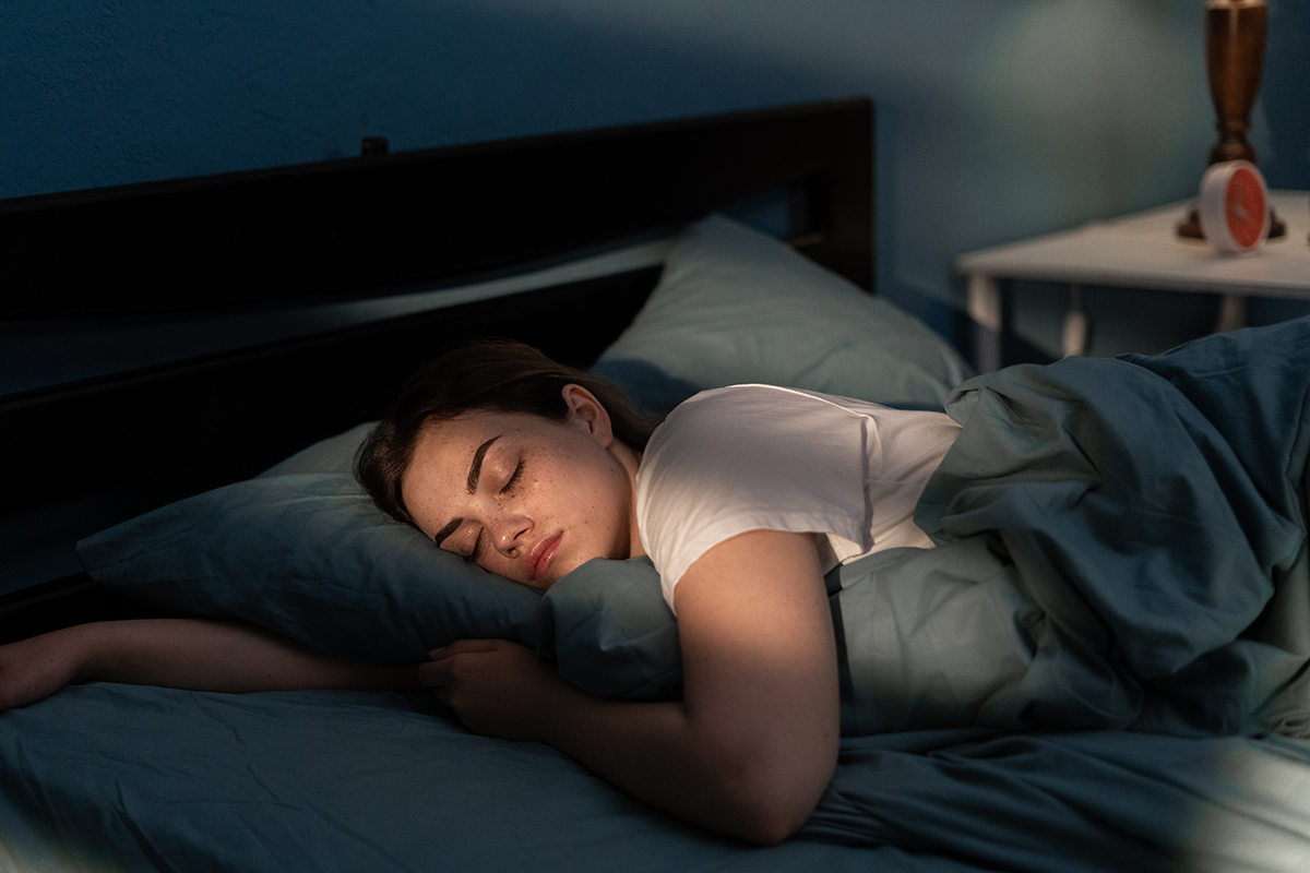 Woman sleeping soundly in bed with morning light filtering through the window.