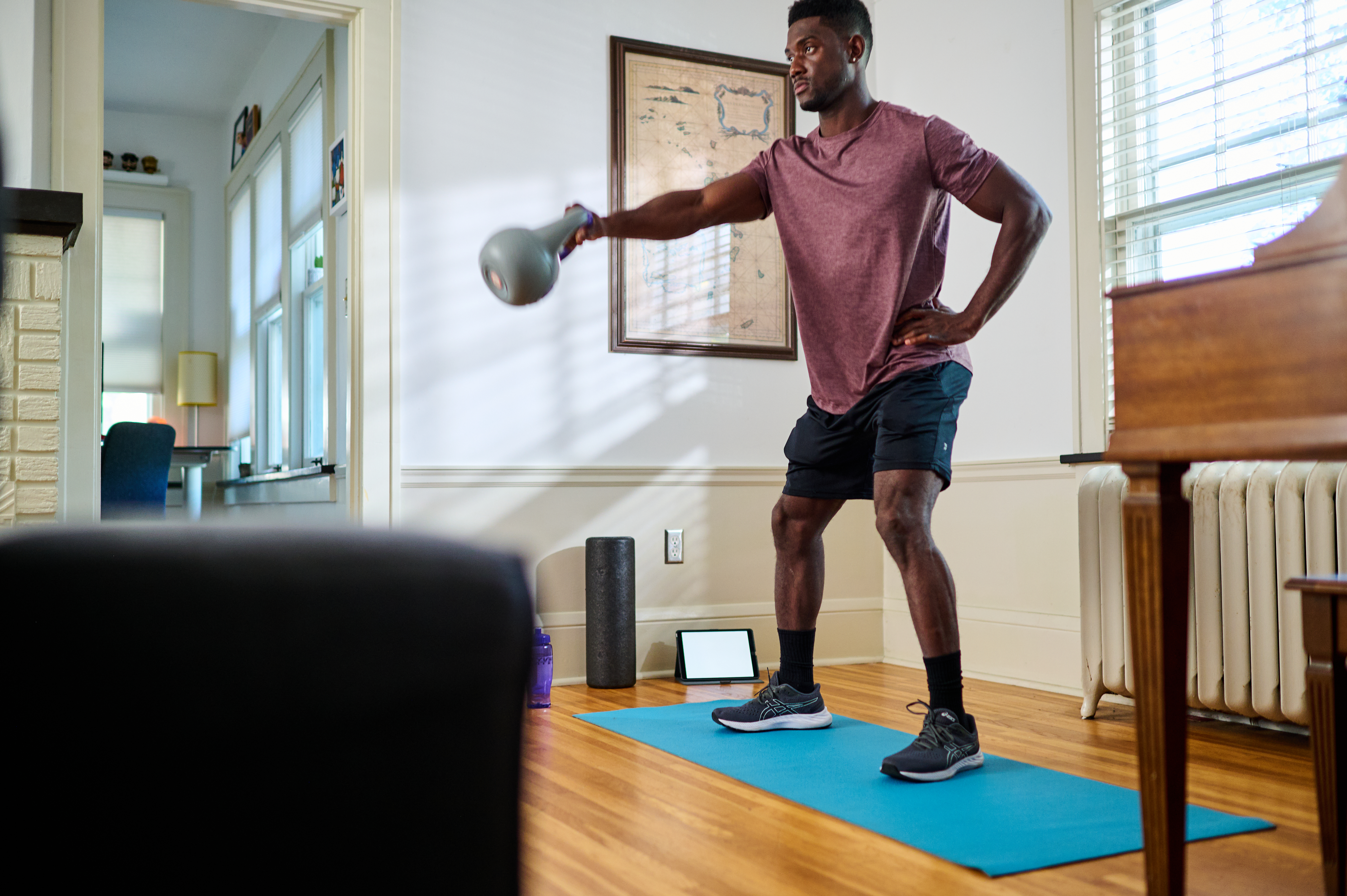 Man performing a kettlebell swing during an at-home workout.