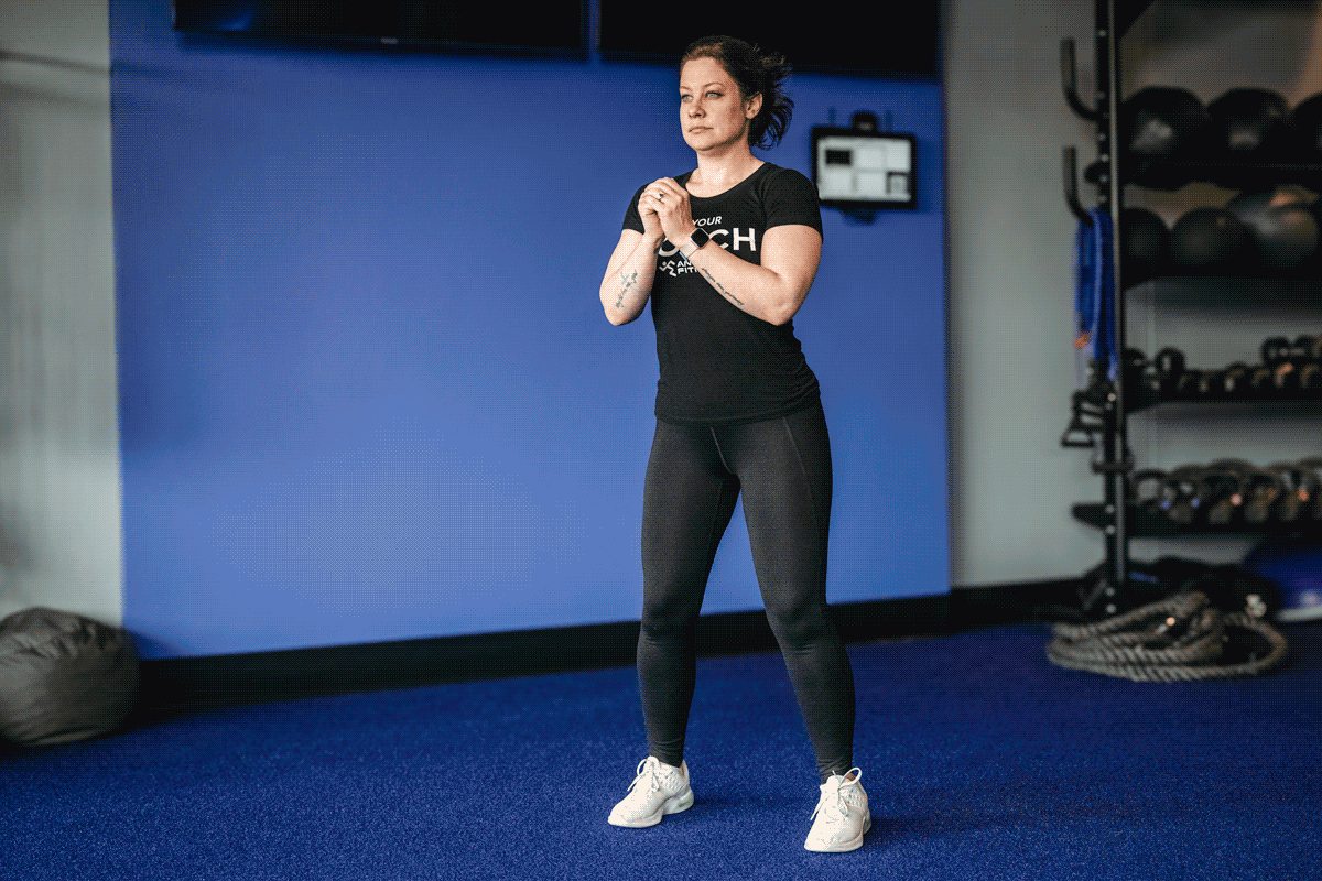 Personal trainer performing squats, engaging quads, hamstrings, and glutes.