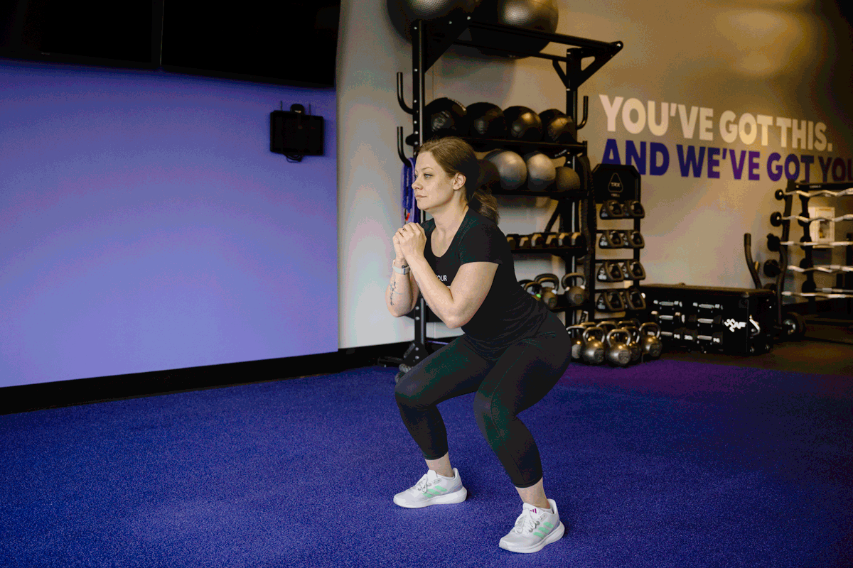 Fitness instructors demonstrate squat mobility drills to increase lower body flexibility and strength in a standing position.