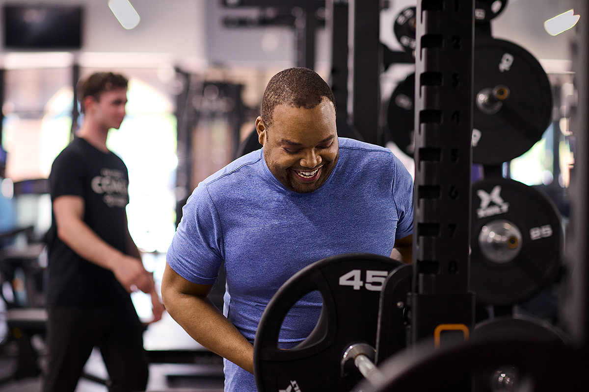 Man loading weights onto a barbell on a rack, preparing for a strength training workout.