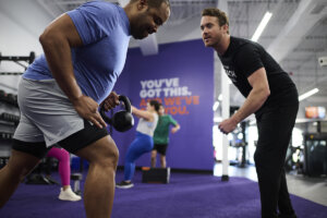 An Anytime Fitness Coach working with a member doing a kettlebell-focused resistance training workout.