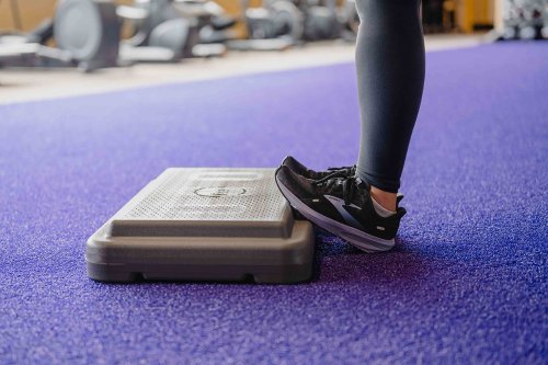 AF_CoolDown-Calves Coach standing and facing an exercise platform, toes on edge of platform with heels on the floor.