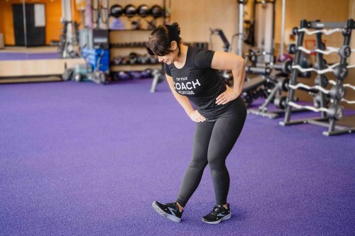 AF_CoolDown-Hamstrings Coach standing in a gym doing a hamstring stretch.