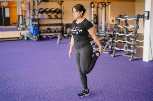 AF_CoolDown-Quads Coach standing in a gym doing a quad stretch.