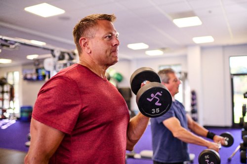 Man lifting weights in a gym setting.