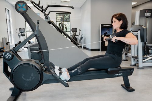 AnytimeFitness_RowingMachine_Step3 Coach Heather demonstrating the finish on a rowing machine.